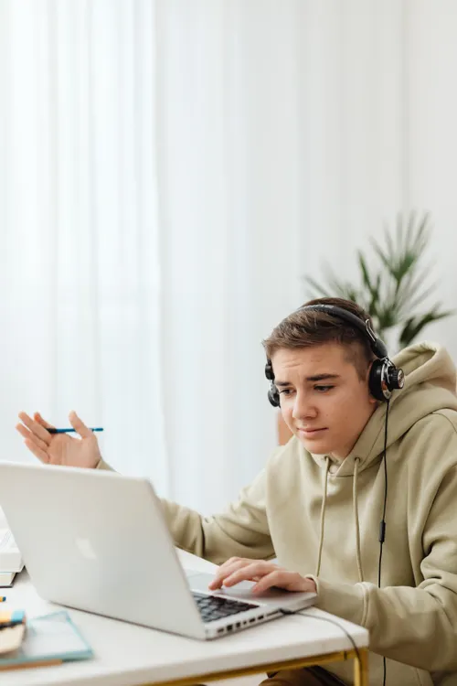 Teen student with headphones learning online on a laptop